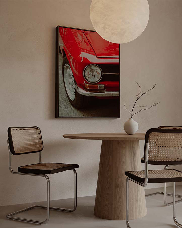 Vertical canvas wall art featuring a close-up of a red vintage classic car with round headlight, chrome bumper, and retro details. Printed on high quality canvas in modern japandi living room