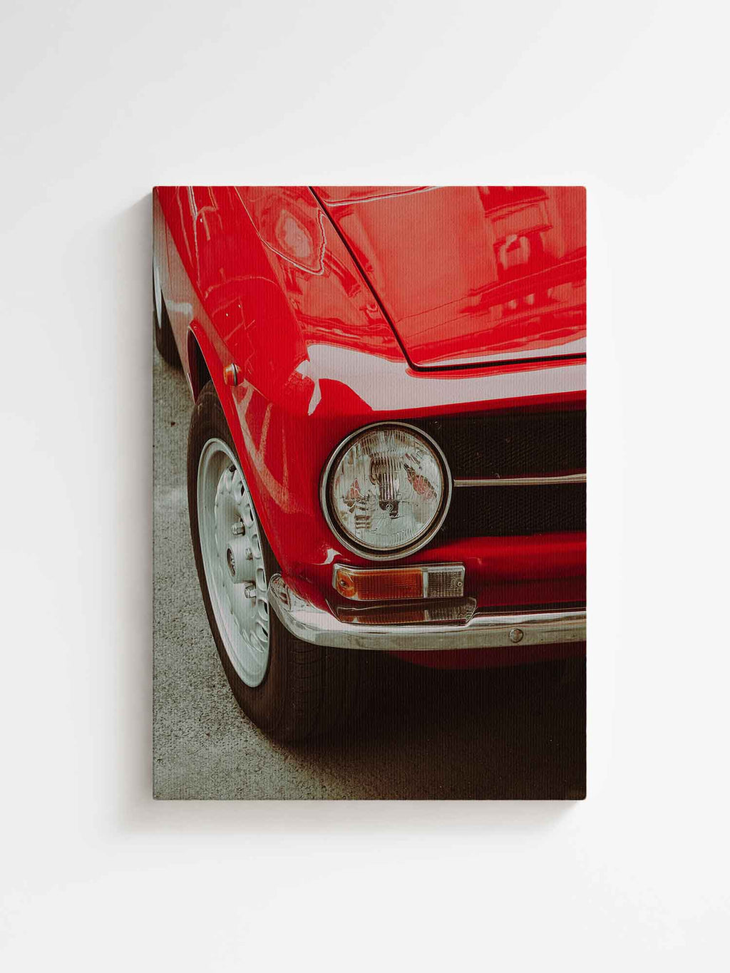 Vertical canvas wall art featuring a close-up of a red vintage classic car with round headlight, chrome bumper, and retro details. Printed on high quality canvas