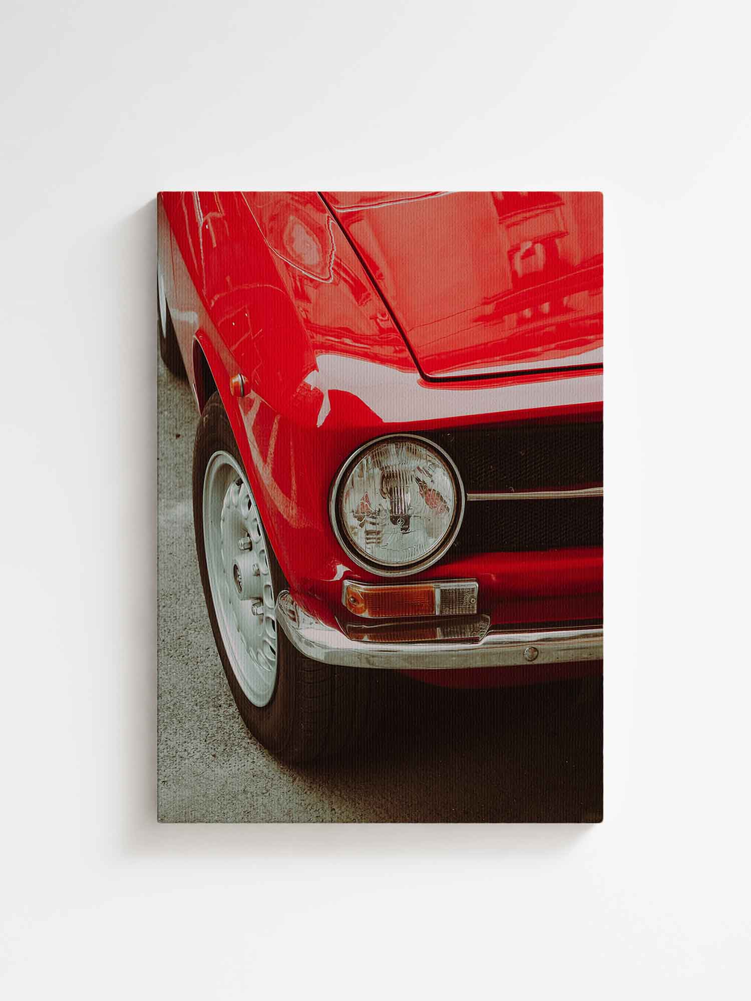 Vertical canvas wall art featuring a close-up of a red vintage classic car with round headlight, chrome bumper, and retro details. Printed on high quality canvas